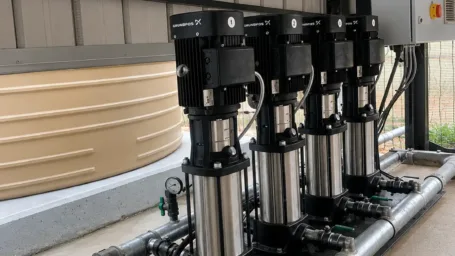 An industrial four-pump vertical multistage inline booster system built on a steel skid with an integrated electrical control panel.